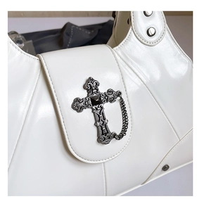 Close-up of gothic silver cross and metal chain detail on white leather handbag