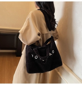 Detail of black corduroy tote bag with TOTE BAG lettering and adjustable shoulder strap