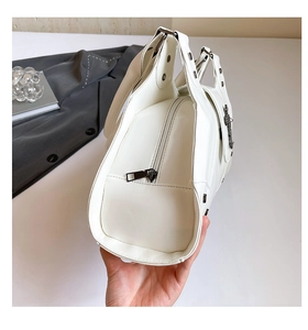Close-up of white biker handbag with dark silver zippers and embossed details