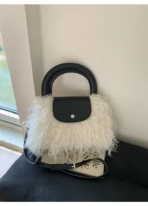 Close-up of plush white faux fur handbag with black leather trim and silver metal clasp