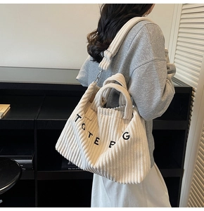 Detail of white corduroy tote bag featuring black letter embroidery and adjustable strap