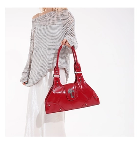 Close-up of a glossy red patent leather handbag featuring a metallic cross pendant detail