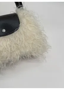 Detailed view of plush faux fur texture and black leather flap with silver magnetic buckle