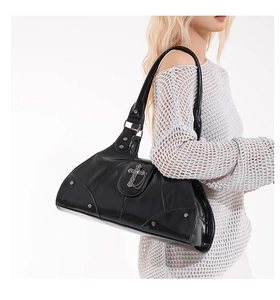 Close-up of black glossy shoulder bag with silver metal cross and rivet details