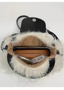 Interior view of black leather plush crossbody bag with white faux fur fringe and essentials