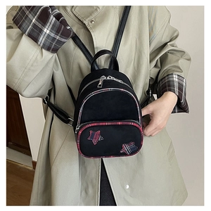 Dettaglio mini zaino scozzese con toppe a stella su un trench coat color beige