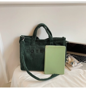 Detail of green corduroy tote bag with TOTE embroidery showing large capacity storage