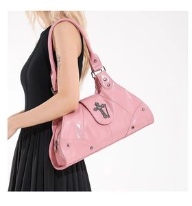 Close-up of pink patent leather handbag with silver cross pendant and metal studs