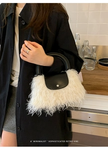 Detail of white faux fur handbag with black leather handle and silver metal clasp
