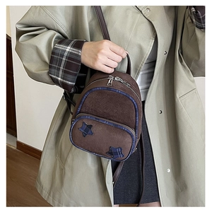 Dettaglio di un mini zaino in pelle scamosciata marrone con bordi a quadri e stelle