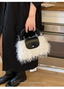 Detailed close-up of plush faux shearling handbag with black leather handle and flap