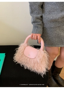 Detail of pink faux fur handbag with smooth leather top handle and silver magnetic closure