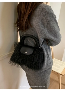 Chic black plush and leather shoulder bag with silver buckle worn by a model