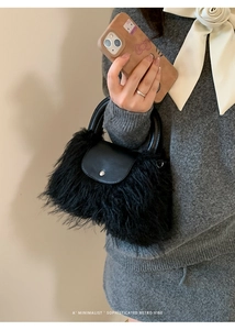 Detail of black faux fur handbag featuring synthetic leather handle and silver snap button