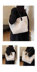 Detailed texture of white corduroy tote bag with black faux leather shoulder straps