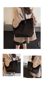 Detail of black corduroy tote bag showing ribbed texture and leather handles on model