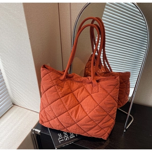 Gros plan du sac cabas matelassé orange rouille avec motif en losanges et miroir