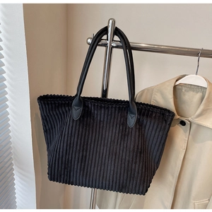 Detail of reinforced teardrop stitching and black faux leather handle on corduroy tote