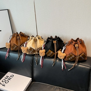 Vintage drawstring bucket bags in four colors with cute bear charms on a leather sofa