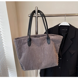 Close-up of ribbed corduroy texture and black leather strap on a large grey tote bag