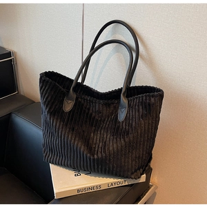 Close-up of black corduroy tote bag texture with elegant leather shoulder handles