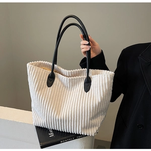 Detail of off-white corduroy tote bag showing textured fabric and black leather handles