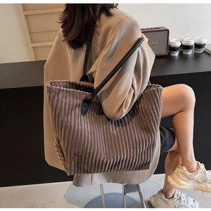 Detail of coffee brown corduroy tote bag featuring slim black leather handles on a table