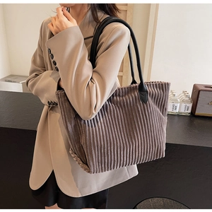 Detailed texture of dark brown corduroy tote bag with black leather handles for women