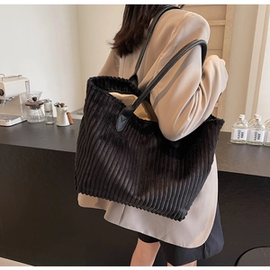 Macro detail of black corduroy tote bag with durable leather straps on model shoulder