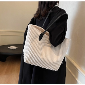 Detailed shoulder view of off-white corduroy tote bag with black leather straps