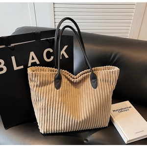 Detailed texture of beige corduroy tote bag with black leather straps on sofa