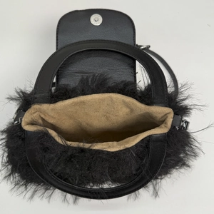 Black faux fur handbag with tan lining and silver magnetic closure in top-down view