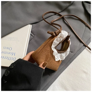 Détail d'un mini sac bandoulière en daim marron avec bordure en dentelle blanche