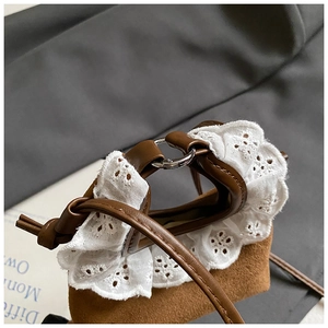Détail du mini sac en daim marron avec bordure en dentelle blanche et anneaux en métal