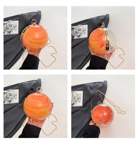 Dettaglio della borsa sferica con texture in marmo arancione e manico ad anello oro