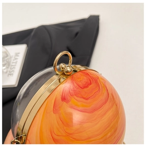 Dettaglio della borsa da sera sferica con trama in marmo arancio e chiusura ad anello d'oro