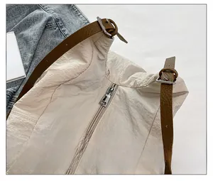 Close-up of smooth metal zipper and adjustable brown leather strap on nylon tote bag