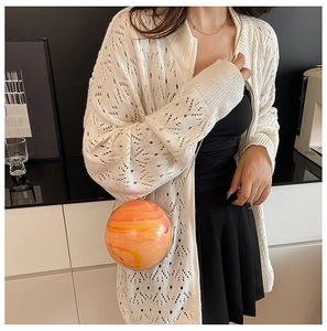 Dettaglio di una mini borsa rotonda con trama marmorizzata arancione e tracolla a catena