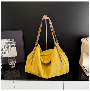 Detail of yellow nylon tote bag with pleated texture and adjustable brown shoulder strap