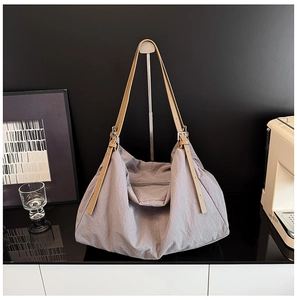 Detailed shot of grey nylon tote bag with adjustable brown leather straps on display