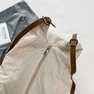 Detail of beige wrinkled nylon tote with brown faux leather strap and silver metal buckle