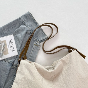 Detailed top view of off-white nylon tote bag with brown leather straps on white surface
