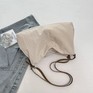 Detailed texture of beige nylon tote bag with crinkled fabric and slim brown strap