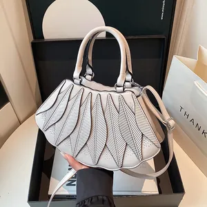 Detailansicht der cremefarbenen Handtasche mit Blatt-Design und verstellbarem Riemen