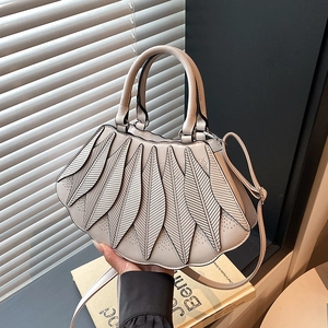 Detail der blattartigen Faltenstruktur der beigen fächerförmigen Tasche im Tageslicht