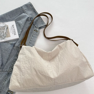 Macro shot of cream nylon tote bag texture with brown straps and artistic prop layout