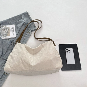 Detail view of large beige pleated nylon tote bag with brown straps and casual items