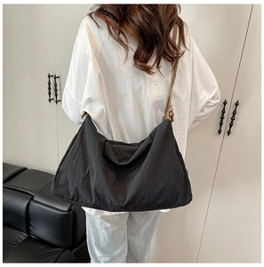 Detailed back view of a large black nylon tote bag with adjustable brown strap