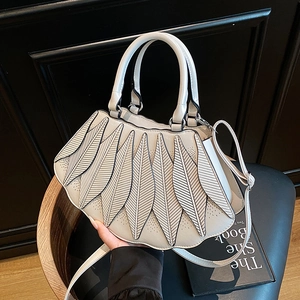 Detail der cremeweißen fächerförmigen Handtasche mit Blatt-Patchwork auf einem Holzstuhl