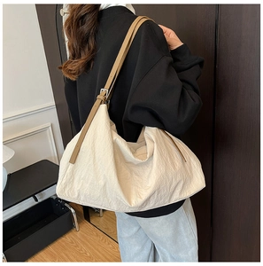 Detail of adjustable brown leather strap and silver buckle on a beige nylon tote bag
